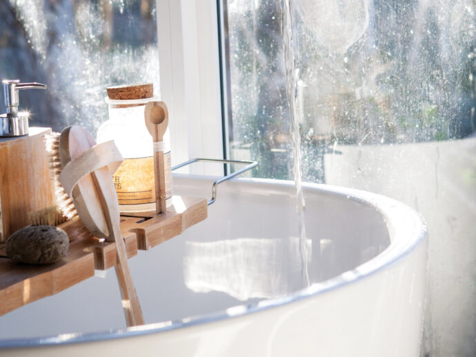 hydrated sink in a bathroom with many facial cleansers and soaps.